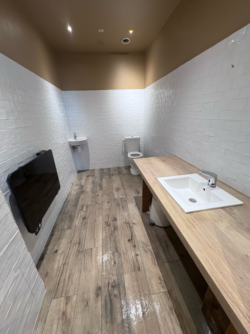 Sanitaire professionnel carrelé en briquettes blanches avec sol parquet imitation bois